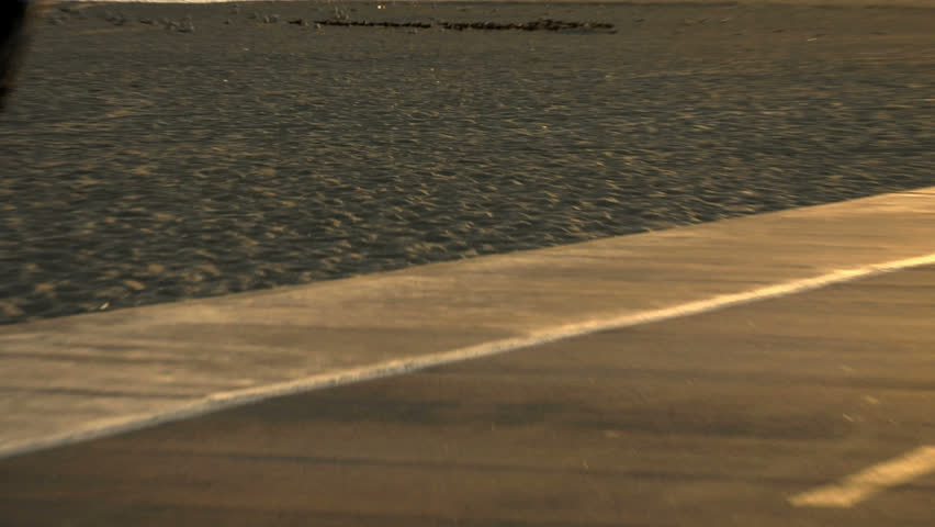 A man runs on the beach at sunset.
