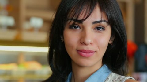 Central Asian woman with dark hair smiles close in cafe