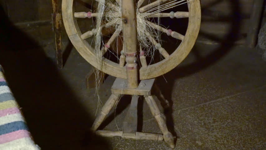 Spinning is in Ukrainian Hut. on the Spindle Wound Yarn. Wooden Spinning Wheel in the Ukrainian Hut. Panorama of the Spinning Wheel Up. Crafts Ancient Masters. Wooden Household Items. Skill Yarn.