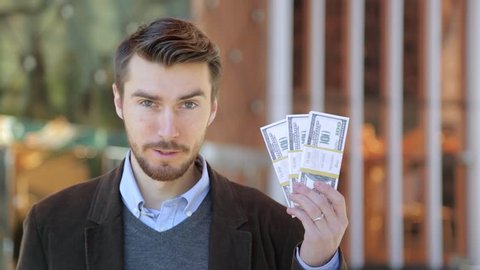 Happy attractive man holding in his hand bundles of money cash dollars