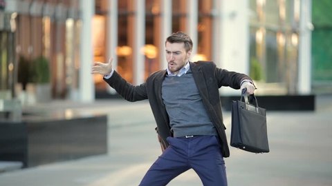 Attractive man with a beard and briefcase dancing in the street