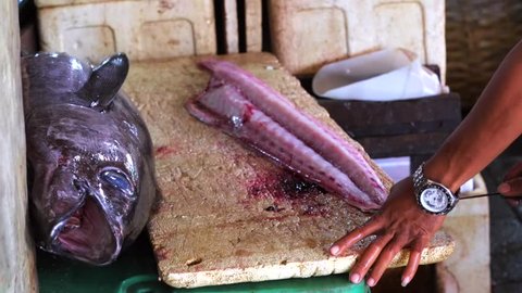 Man cutting fresh-caught fish Mahi Mahi. Fish preparation. Tuna fish. Jimbaran Fish Market. Bali, Indonesia
