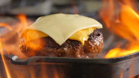 Homemade burger with cheese on a grill pan, slow motion 