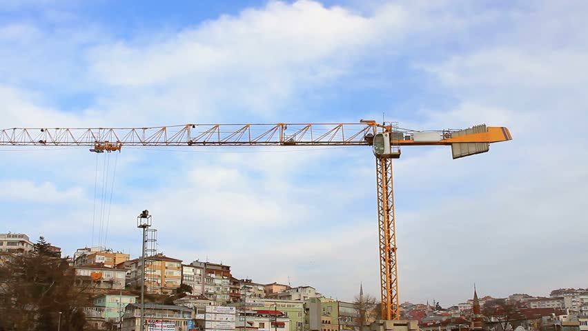 Yellow hoisting tower crane by the blue sky