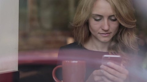 Woman using app on smartphone smiling and texting on mobile phone.