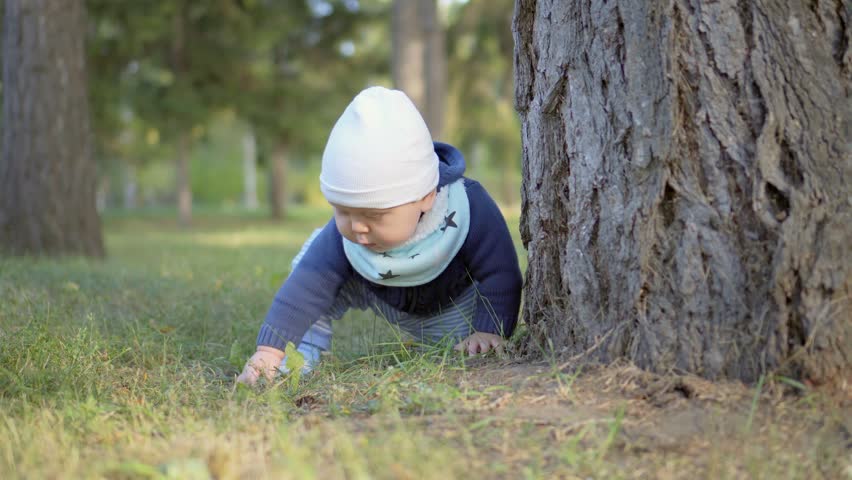 Baby sitting on the grass and touching her.