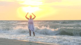  Happy woman enjoys the sea, the sun, the waves.  Seascape during Sunrise. Beautiful Sunny Reflection on the Sea. Slow motion 240 fps. Full HD 1080p. High speed camera 