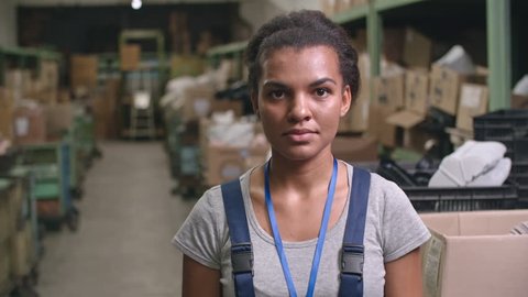 Portrait of Latin-American female worker standing in warehouse posing for camera and laughing