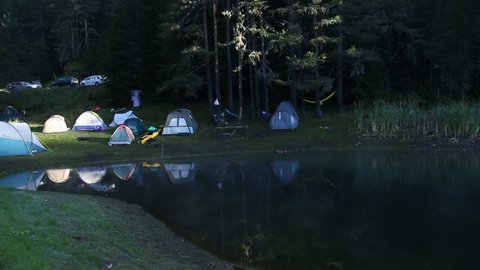 Tents in campsite near to the mountain lake, sunrise morning with drifting fog