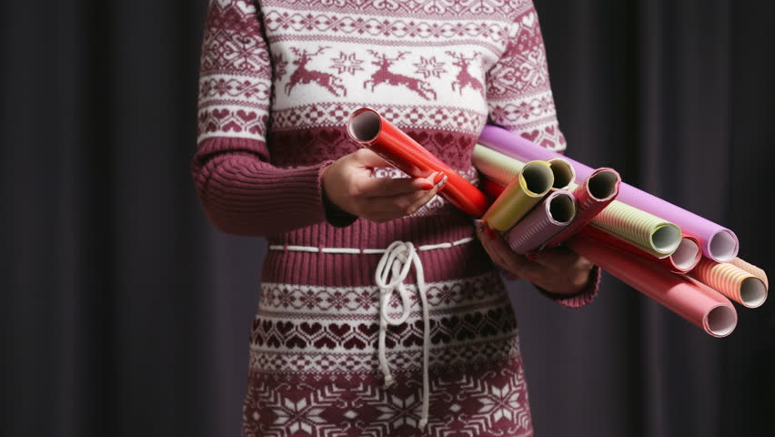 Clumsy unrecognizable girl in deer sweater shoose wrapping paper roll