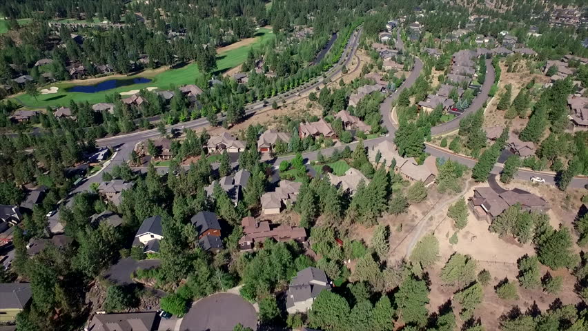 Aerial shot tilt up revealing Bend Oregon and looking to the west.  Aerial view tilting up from residential area looking to the west at the Cascade Mountains in the Summer.