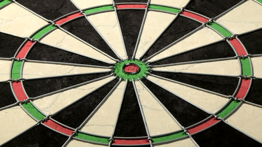Medium shot of a dart board from below, three darts with a bull's eye