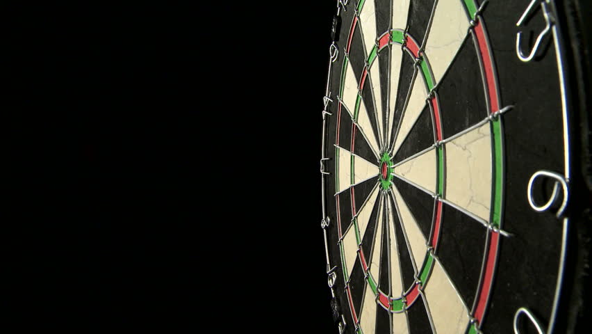 Medium wide shot of a dart board from the side, three darts with a bull's eye