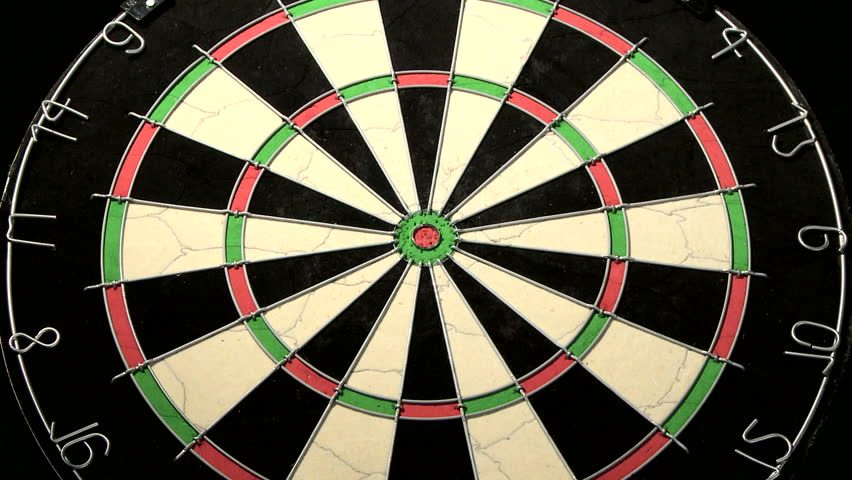 Medium wide shot of a dart board from below, three darts with a bull's eye