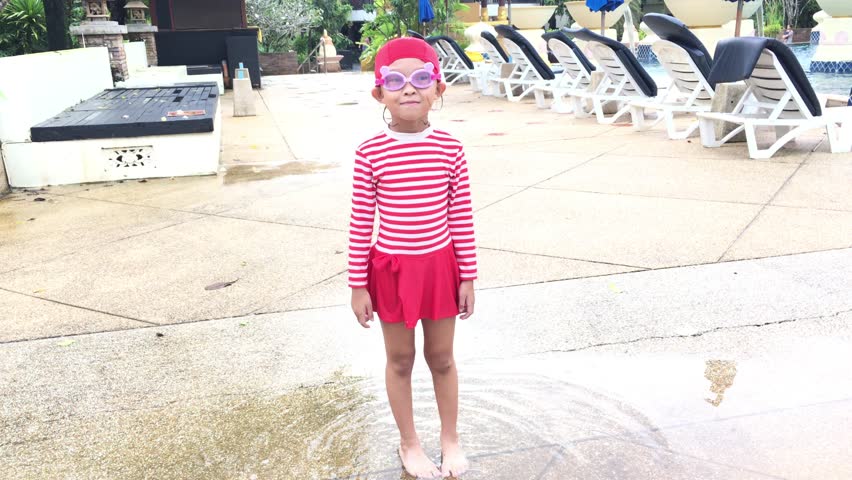cute small girl in red swimming suit walking nearby the pool with stablizer footage.