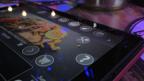 VIENNA, AUSTRIA - APRIL 26, 2016: Close-up shot of woman making an order in restaurant using food menu on digital tablet