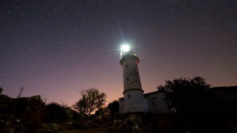 8K. Timelapse of beautiful night landscape with lighthouse with rotating starry sky on a background