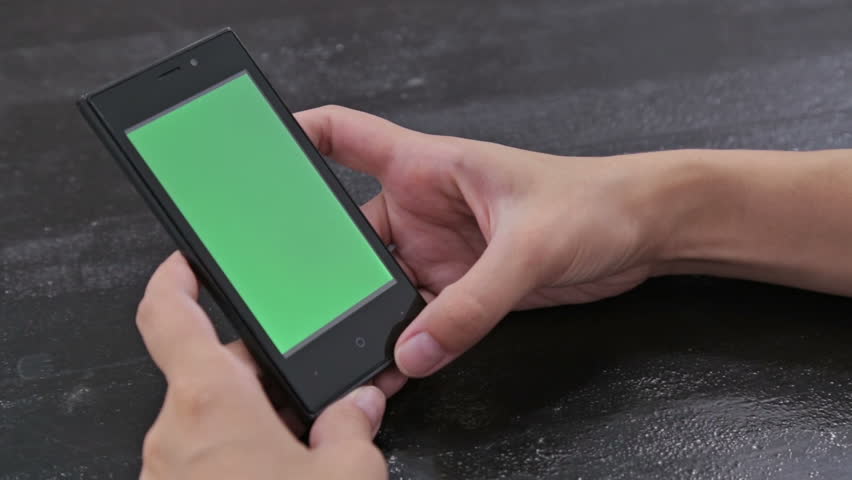 Woman looking at smartphone with green screen. Close up shot of woman