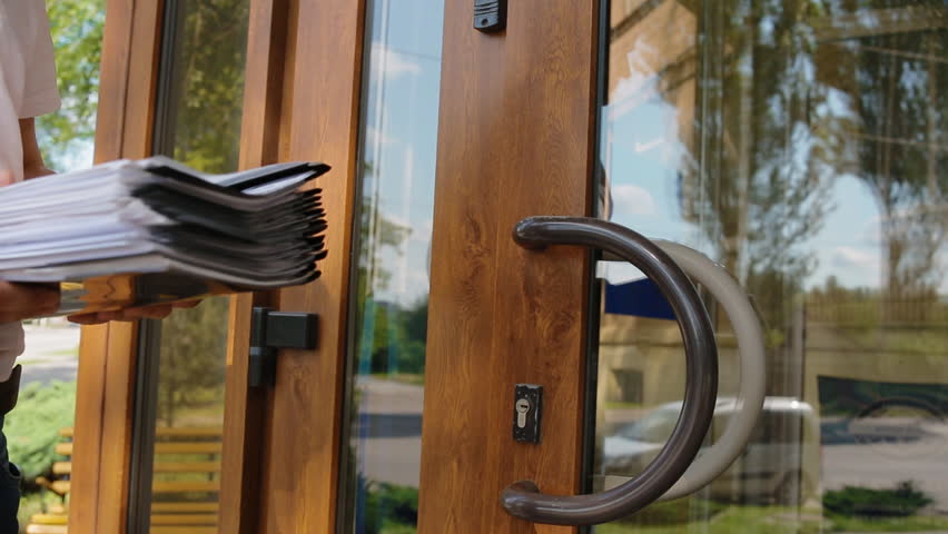 Man with lots of papers enter the door. Closeup.
