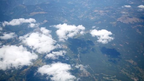Surface of the earth and white clouds, view from a plane window