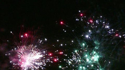 Detail of fireworks, many small explosions in red, green and gold with intermittent flash effect. Slow motion