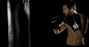 Athletic male working out using heavy punching bag. Slow motion.