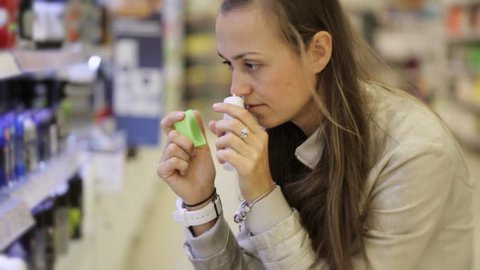 Young caucasian woman choosing deodorant in beauty section of shoping centre. No visible logos and trademarks.