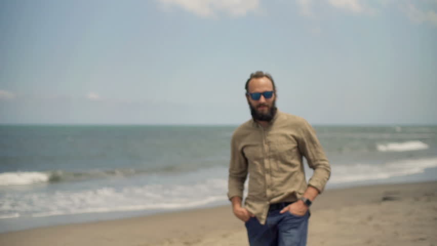 Portrait of young, happy man walking on beach near sea
