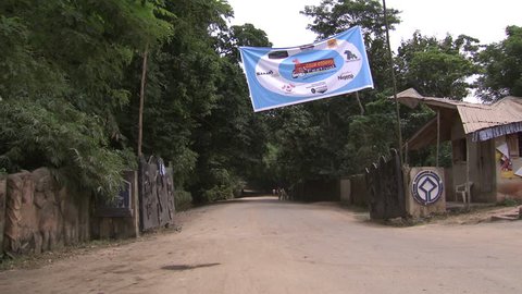 Osogbo, Nigeria - August 2013; Van passes through open gates of the Sacred Grove. Osun Osogbo festival banner.