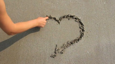 Drawing the heart on the wet sand.