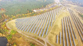 Camera flight over a solar power plant in agricultural landscape. Industrial background on renewable resources theme. Industry of power and fuel generation in European Union. 
