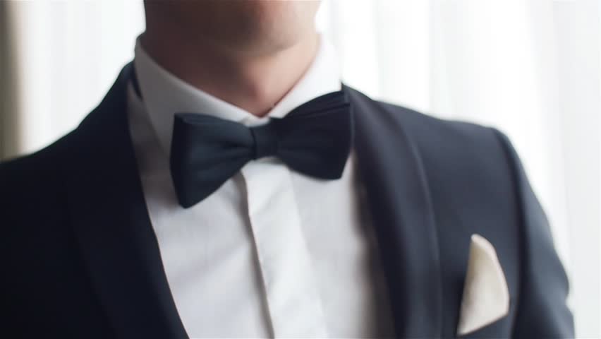 Man straightens bow-tie close up slow motion. Well-dressed young man puts and adjusts classic black bowtie on white shirt no face only torso. Success style confidence establishment luxury life concept Royalty-Free Stock Footage #20943025