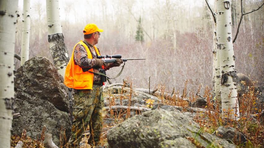 Elk Hunting in a Colorado wilderness during October snowstorm. Hunter raises rifle and looks through rifle scope.