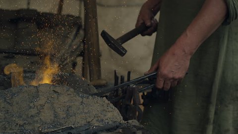Blacksmith Working with Hot Metal. Life of Civilian People at the Village. Medieval Reenactment. Shot on RED Cinema Camera in 4K (UHD).