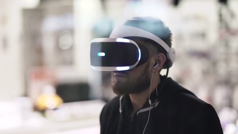 Bearded man uses VR-headset display with headphones for virtual reality game. UHD 4K