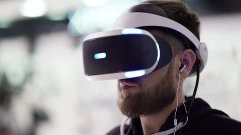 Bearded man uses VR-headset display with headphones for virtual reality game. UHD 4K