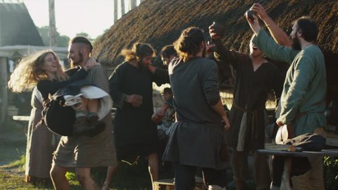 Dressed in Medieval Clothing Group of People Drinking, Dancing and Celebrating. Life of Civilian People at the Village. Medieval Reenactment. Shot on RED Cinema Camera in 4K (UHD).