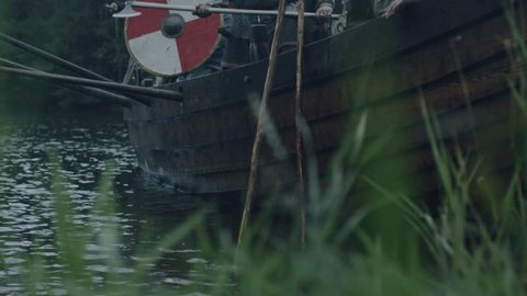 WOLIN, POLAND - 06.08.2016: Viking Warriors Jump off the Row Ship after Arriving to Shore. Slavs and Vikings Festival. Medieval Reenactment. Shot on RED Cinema Camera in 4K (UHD).