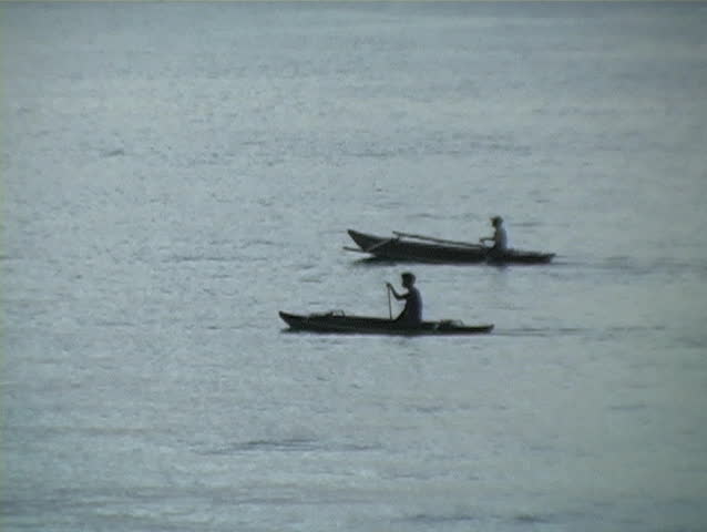 natives in the Philippines rowing their canoes at sunset