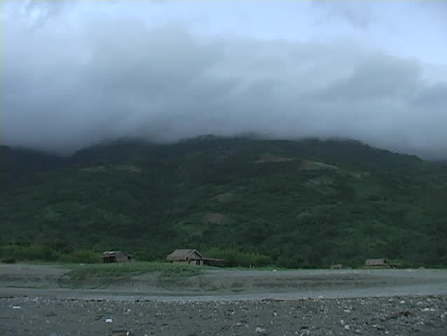 Time lapse of clouds blowing over a mountain and native village in the