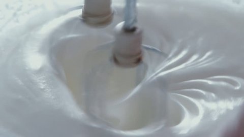 Close up: Whisks whipped egg whites and sugar in the bowl of glass. Whisk in glass bowl of raw egg in slow motion. Whisk for whipping. Whip the egg white: cook at home, make a cake, desserts, meringue