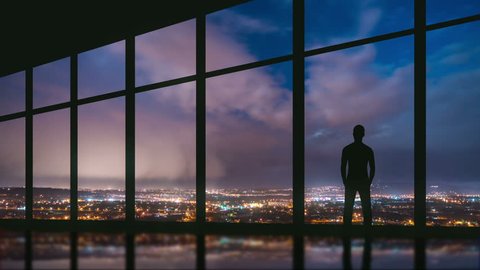 5 in 1 video! The man stand at the panoramic window on the background of night the city. Time lapse. Wide angle