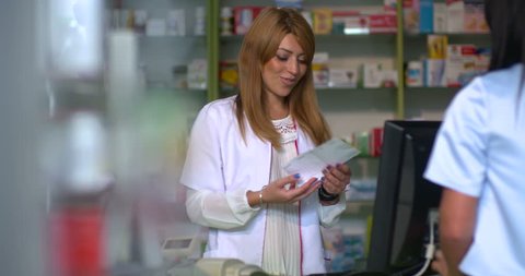 Young attracting female pharmacist selling pills to customer at pharmacy Stock Video