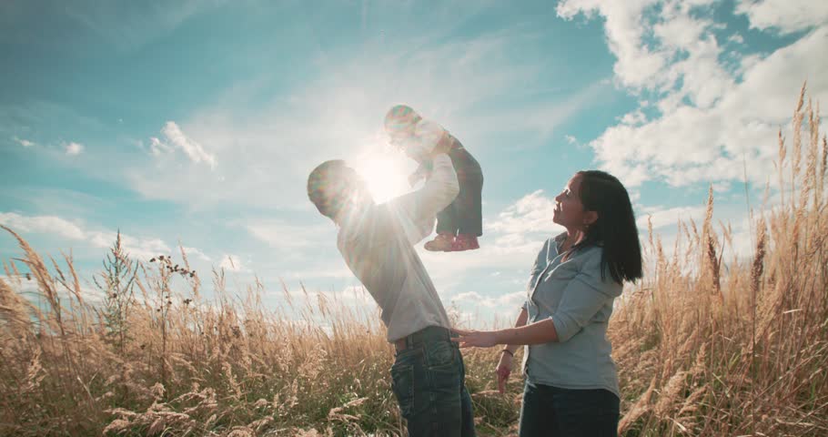Young Asian family in a field with a baby 1 year on hand, the concept of family happiness, beautiful sunlight, sunset, slow motion