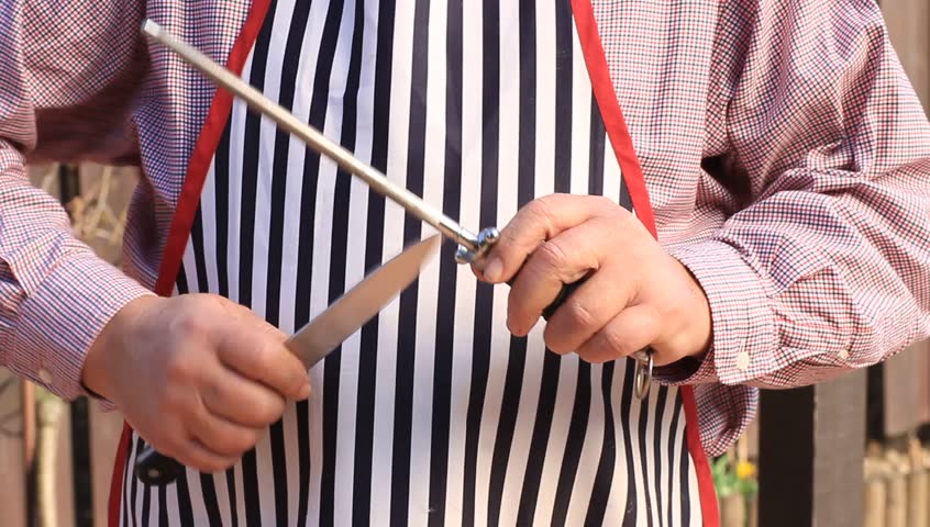 Hands of mature man proffesionally sharpening knife on a honing steel rod