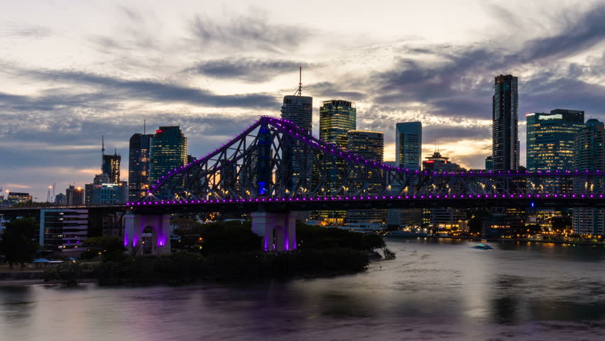 Vibrant dolly night time panorama of Brisbane city with purple lights on Story Bridge, Australia
