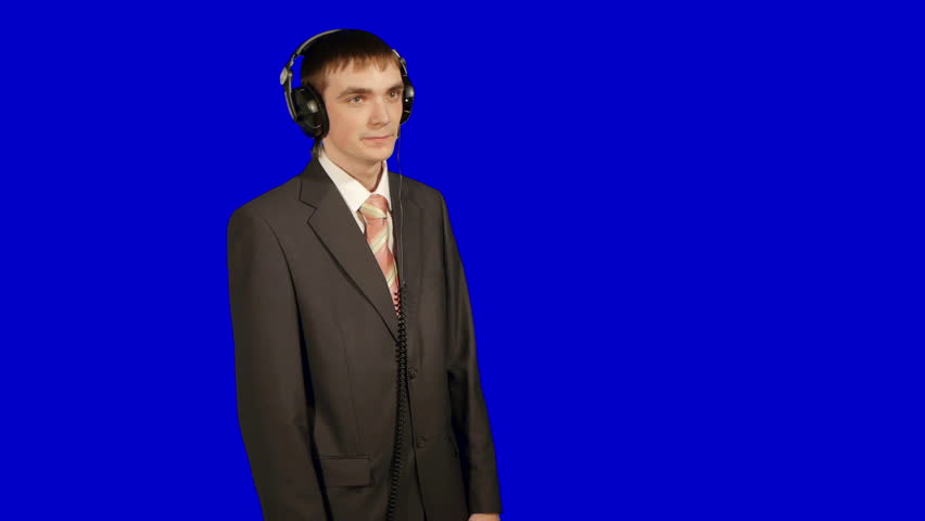 young businessman listen music in headphones, isolated over blue background,
