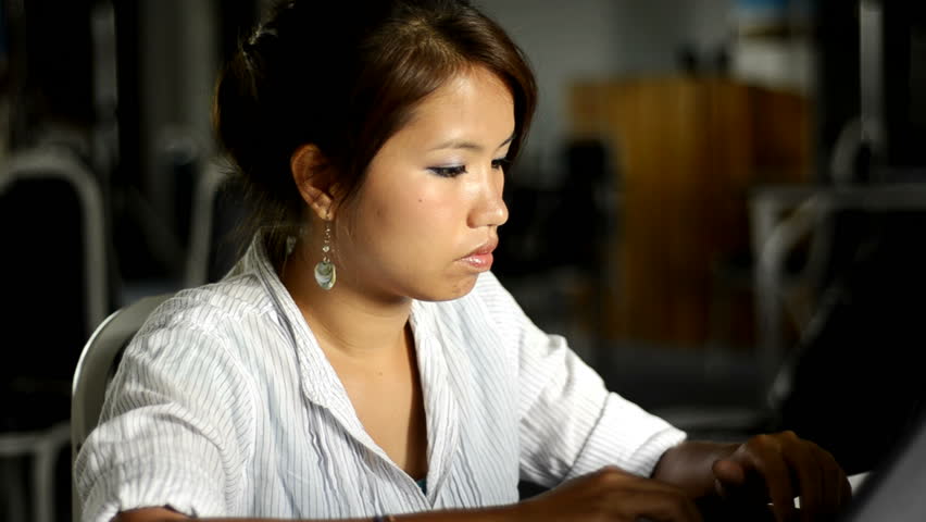 Young Asian woman typing on a laptop.