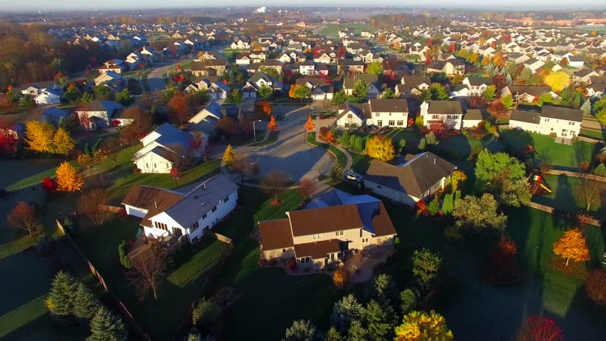 Tranquil idyllic wealthy Autumn neighborhood with frosty rooftops at sunrise, aerial view.