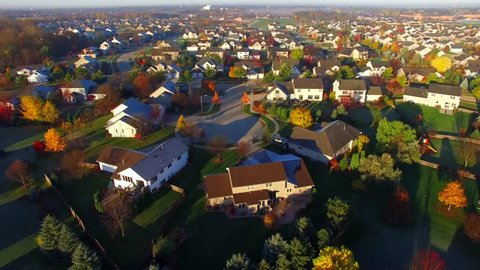 Tranquil idyllic wealthy Autumn neighborhood with frosty rooftops at sunrise, aerial view.